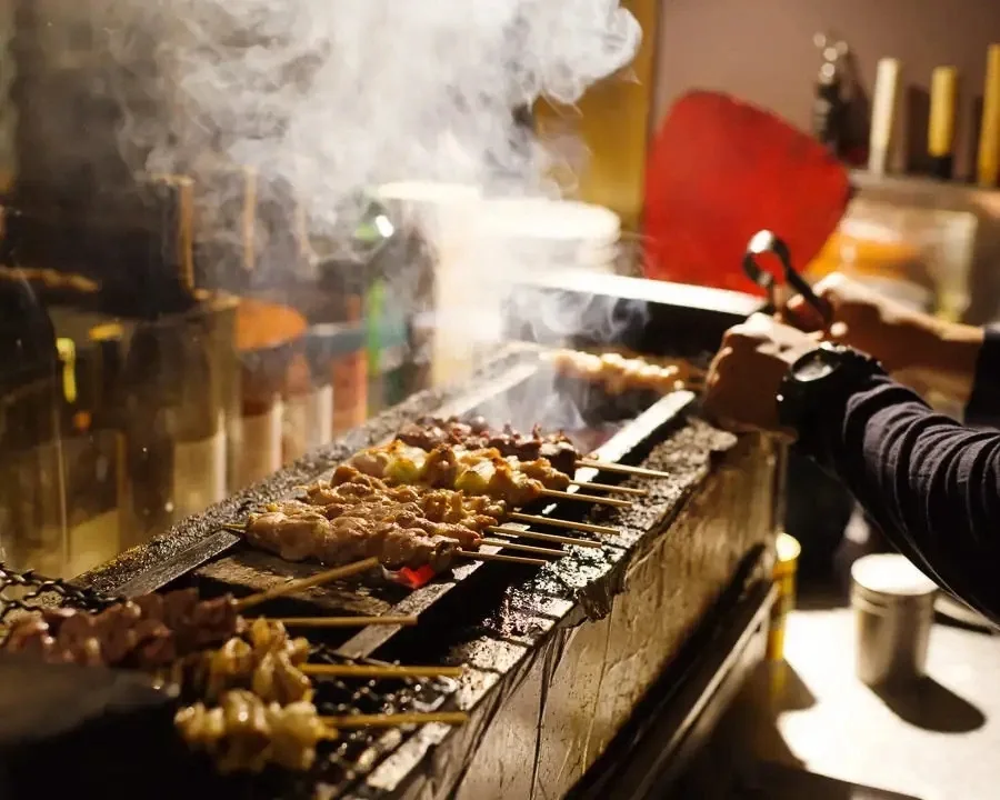 炭火で焼き上げる焼鳥と料理人の手元
