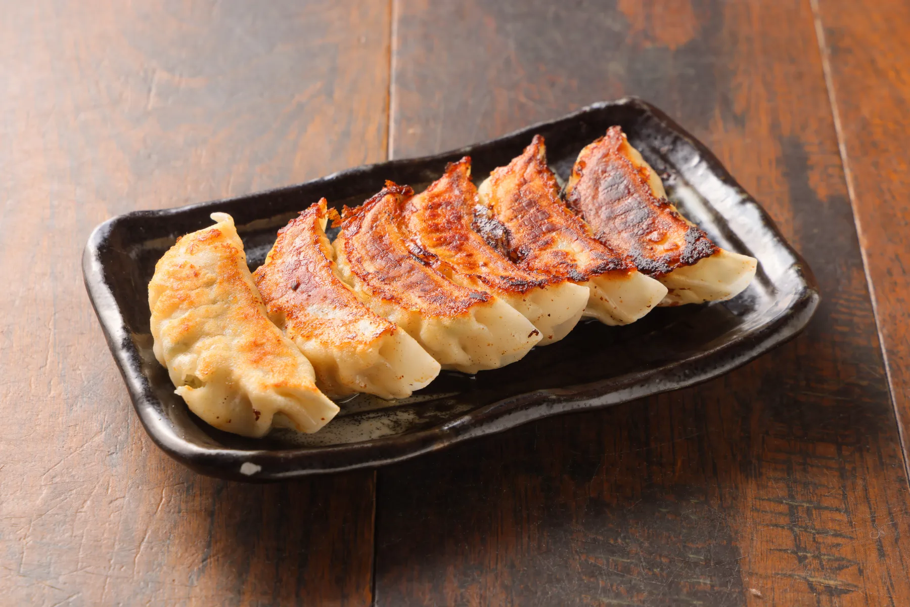 ギョーザ。焼き目のついた餃子を皿に並べた写真