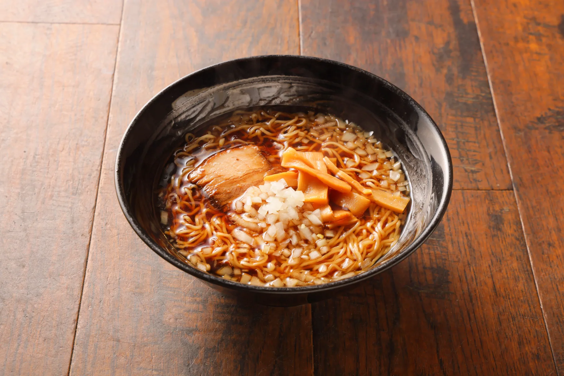 熟成醤油ラーメン。黒い丼の麺料理を斜めから撮影した写真