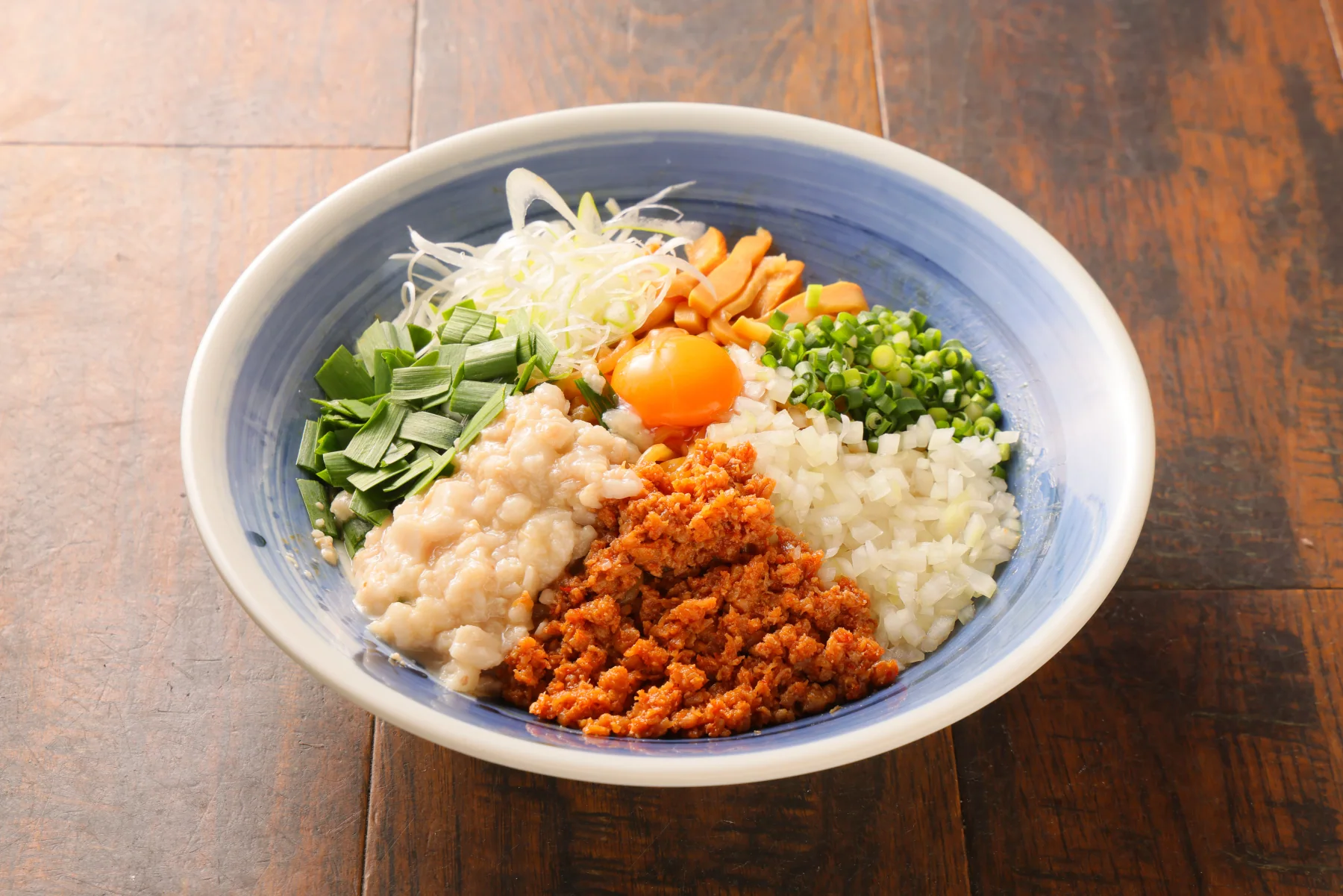 本気の油そば。青い丼に複数の具材を盛り付けた写真