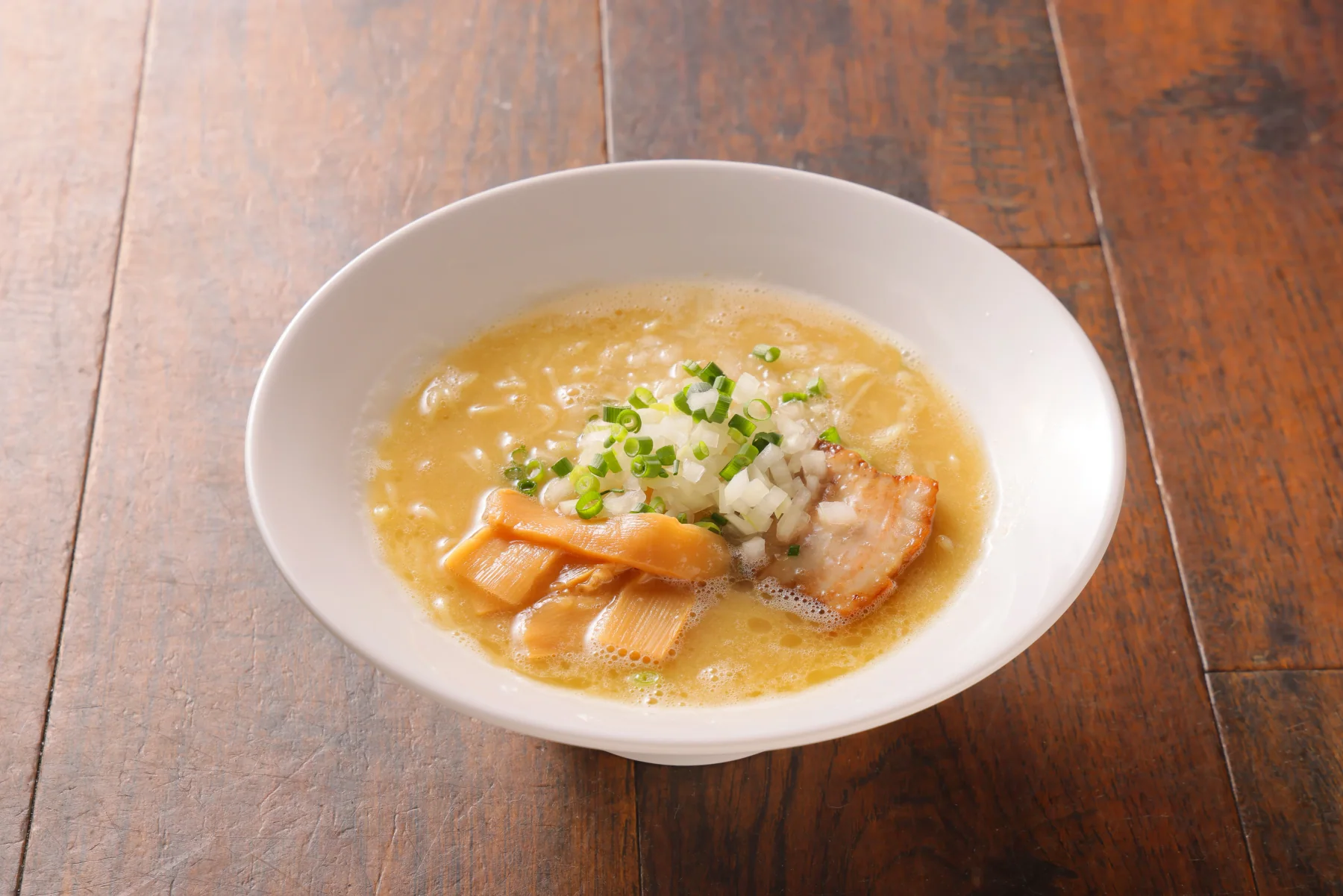 鶏白湯ラーメン。淡い色のスープの麺料理を斜めから撮影した写真
